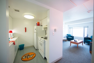 Wide angle view of galley kitchen and furnished living room in 1959 E Street residence.