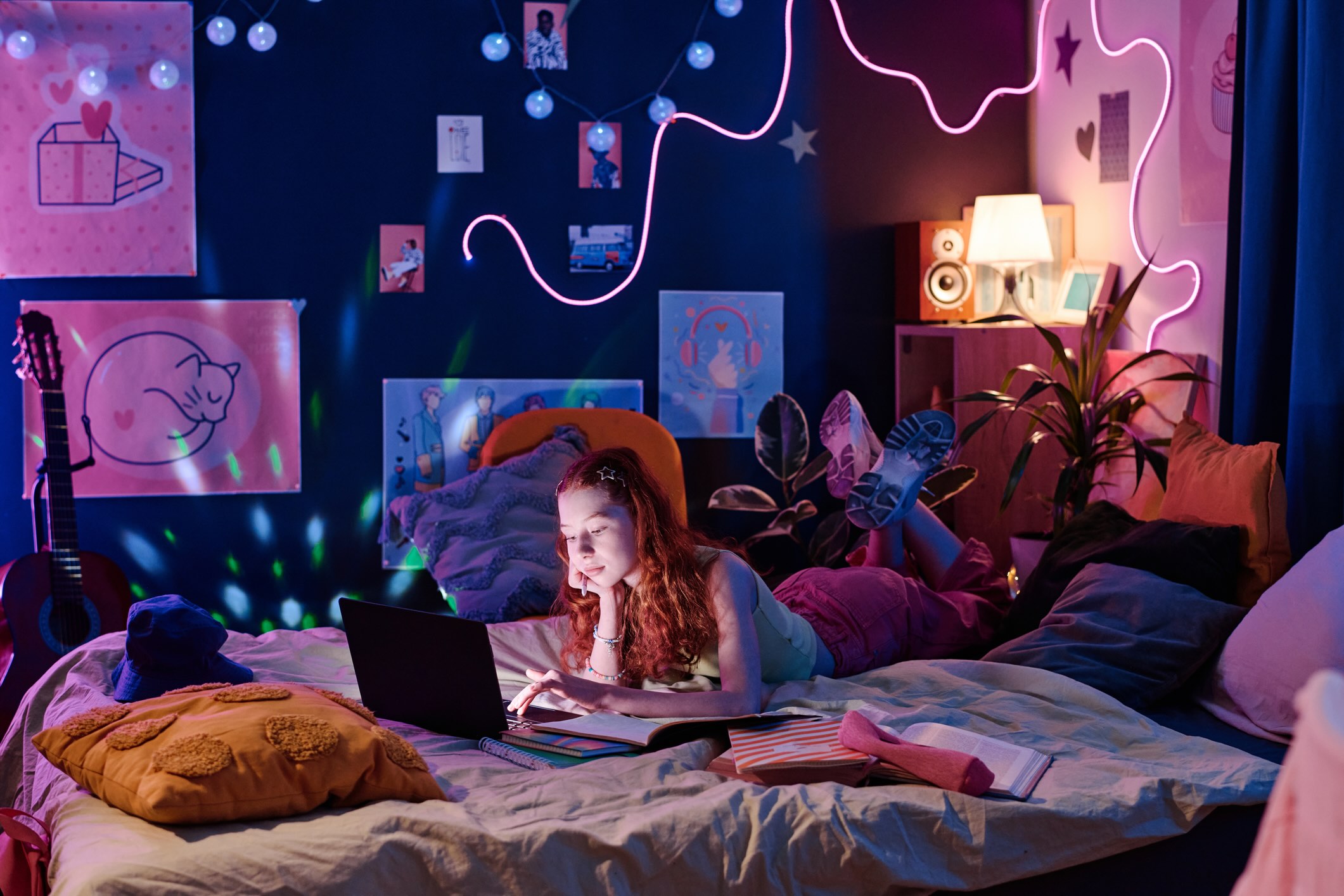 Girl laying on her girly girl college dorm room bed doing homework on her laptop
