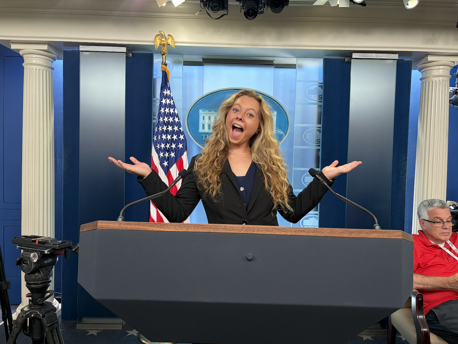 Christine with long blonde hair standing at the White House Press Briefing podium