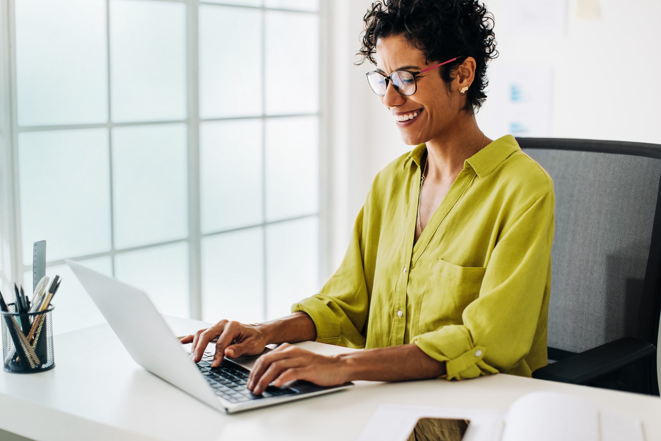 Business woman sitting at her desk, typing on her laptop