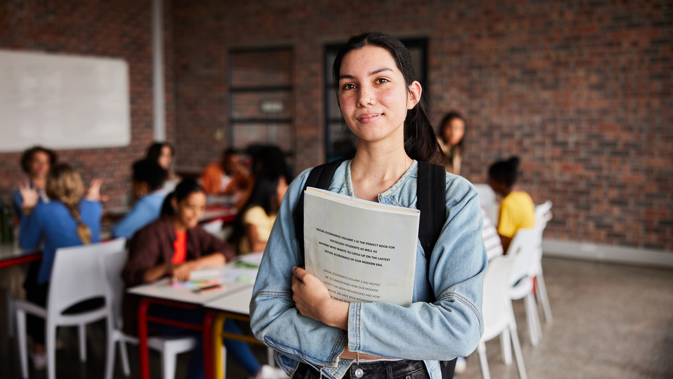 College student in a classroom holding a textbook