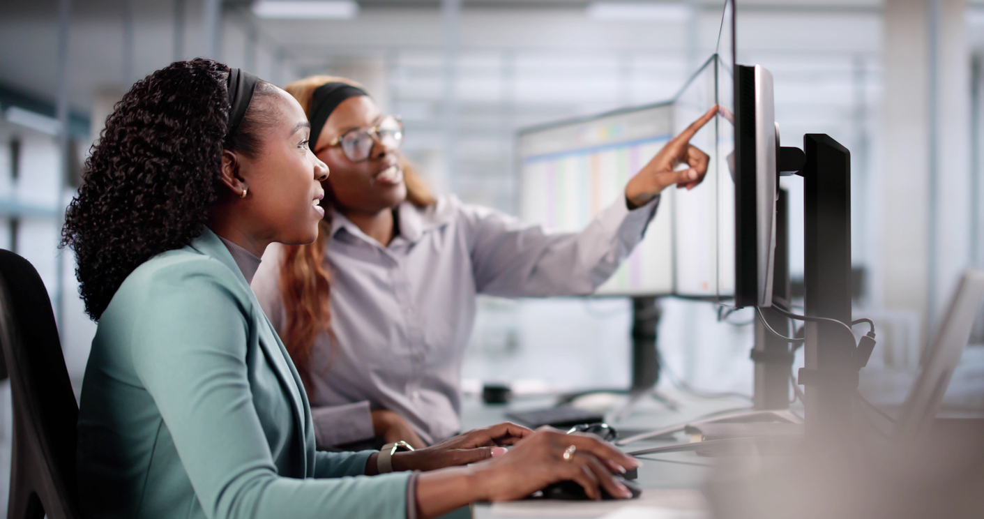 Intern with supervisor learning on a computer in the office