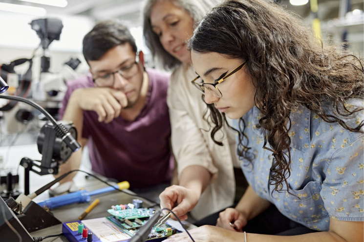 Engineering students working on a program board in a classroom