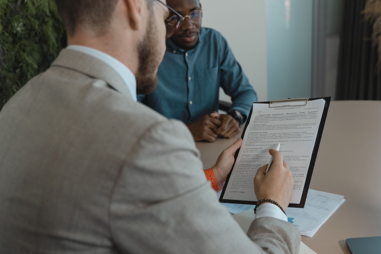 Two men sitting at a table, one is reading a resume