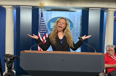 Christine with long blonde hair standing at the White House Press Briefing podium