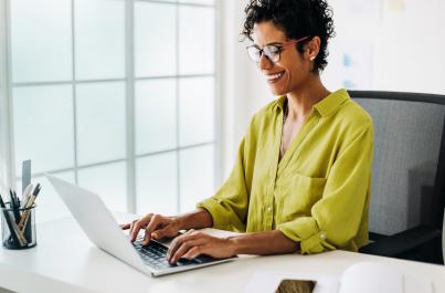 Business woman sitting at her desk, typing on her laptop