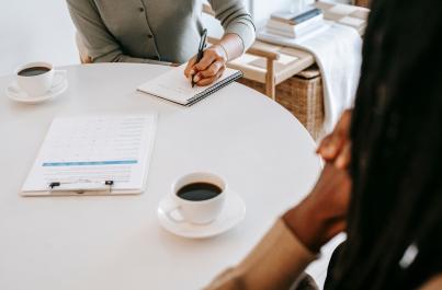 Two people sitting at a table with coffee and paperwork