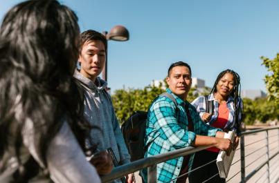 Group of four students standing outside on campus
