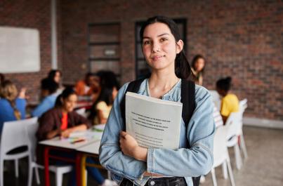 College student in a classroom holding a textbook