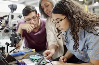 Engineering students working on a program board in a classroom 