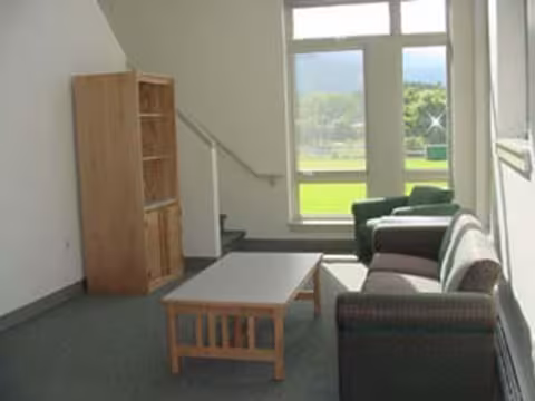 A living room in the campus apartments, with couch, table, and shelf unit