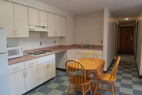 Kitchenette includes white cabinets, a refridgerator and freezer, a microwave, sink and countertops. A table and chairs is included.
