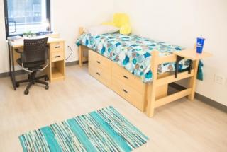 Furnished bedroom with bed, desk, and chair.